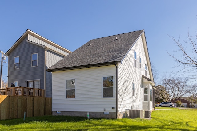 rear view of property featuring a lawn and central air condition unit