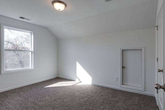 additional living space with dark colored carpet and vaulted ceiling