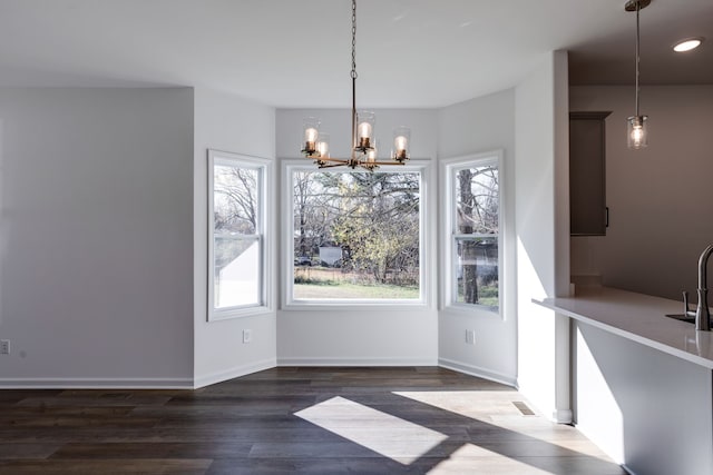 unfurnished dining area with sink, dark wood-type flooring, and a notable chandelier