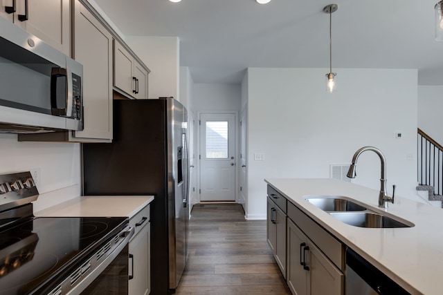 kitchen with gray cabinetry, sink, dark hardwood / wood-style flooring, decorative light fixtures, and appliances with stainless steel finishes