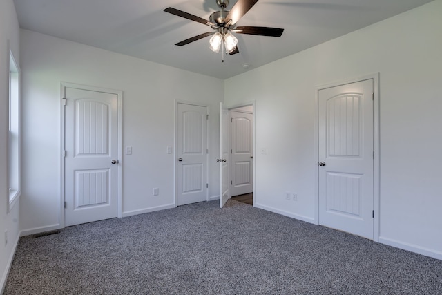 unfurnished bedroom with ceiling fan and dark carpet