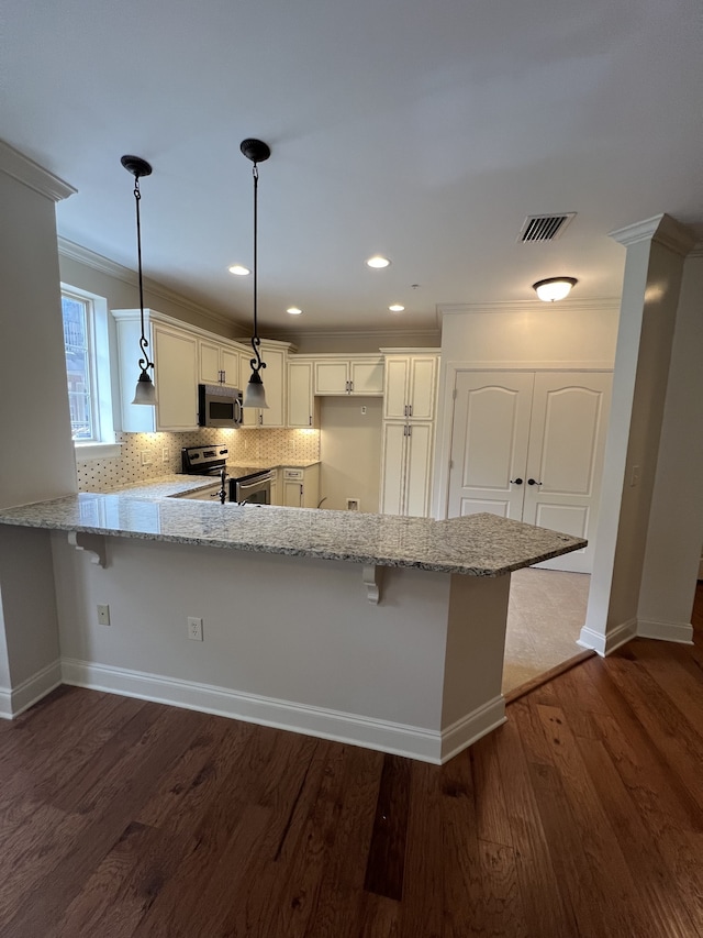 kitchen with light stone countertops, dark hardwood / wood-style flooring, kitchen peninsula, hanging light fixtures, and stainless steel appliances