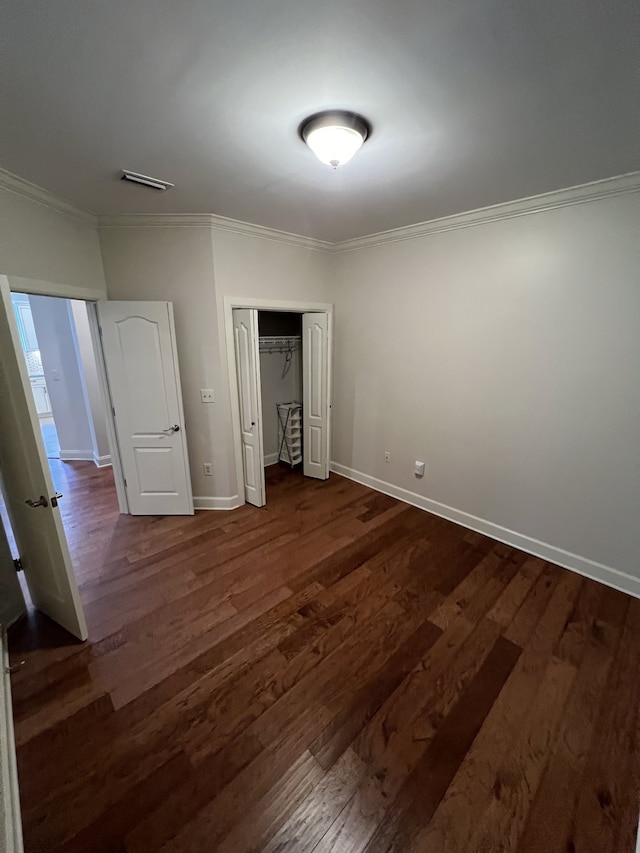 unfurnished bedroom featuring a closet, ornamental molding, and dark hardwood / wood-style flooring