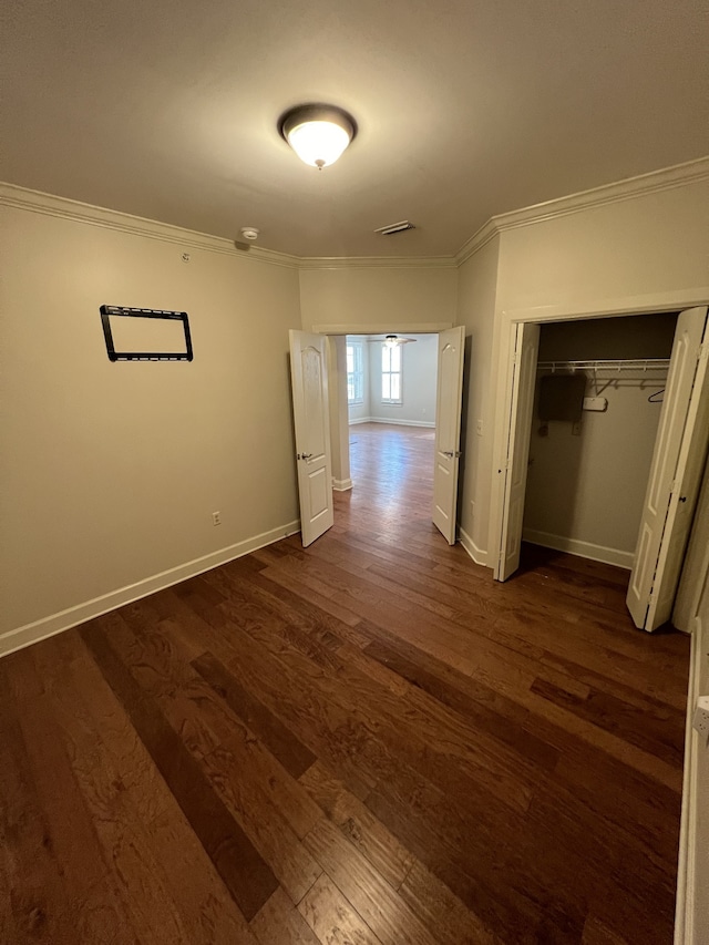 unfurnished bedroom featuring a closet, ornamental molding, and dark hardwood / wood-style floors