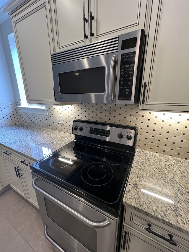 kitchen featuring appliances with stainless steel finishes, light stone countertops, and backsplash