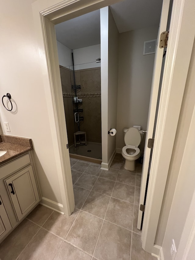 bathroom with vanity, a tile shower, toilet, and tile patterned flooring