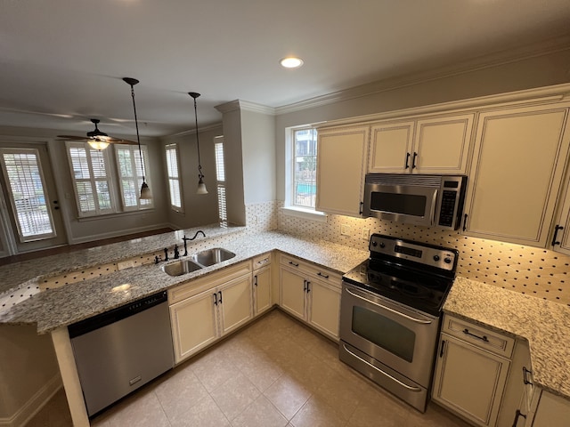 kitchen with appliances with stainless steel finishes, kitchen peninsula, sink, and cream cabinetry