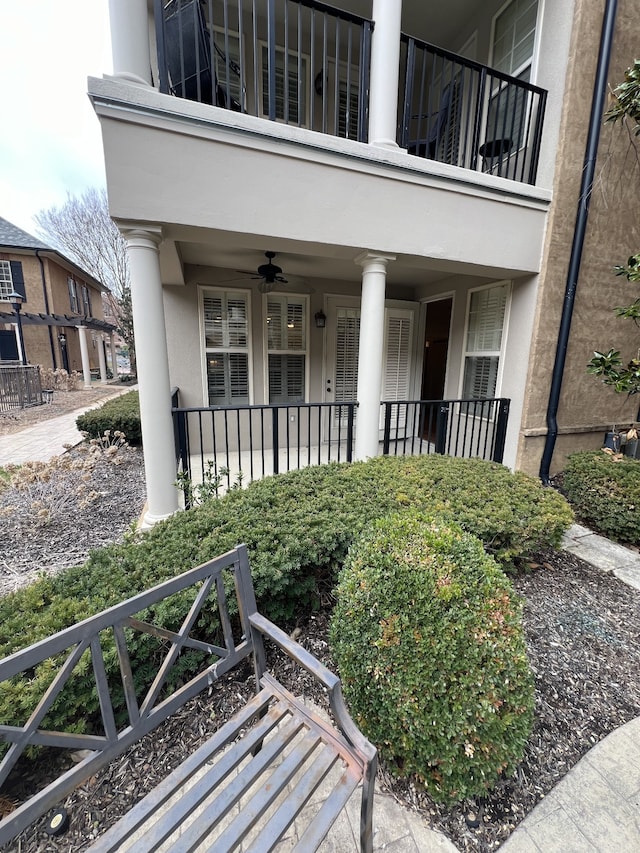 view of exterior entry with ceiling fan and a balcony