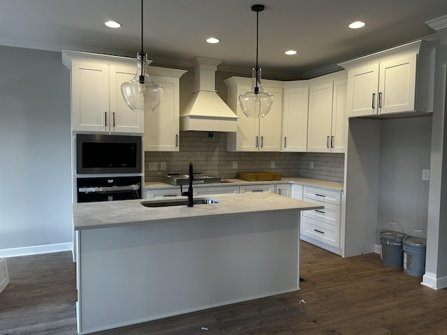 kitchen featuring white cabinetry, a center island with sink, black oven, custom range hood, and pendant lighting