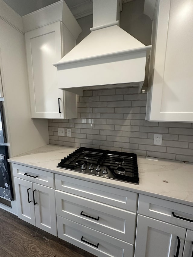 kitchen with tasteful backsplash, white cabinetry, custom exhaust hood, and black gas stovetop