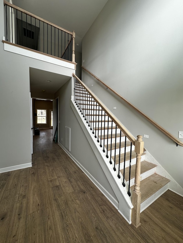 stairs with a high ceiling and wood-type flooring