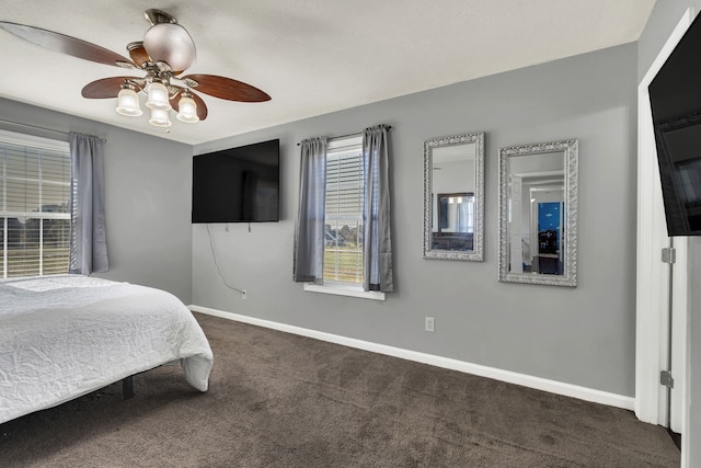 bedroom with ceiling fan, multiple windows, and dark colored carpet