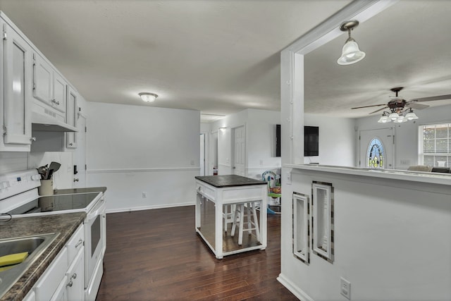 kitchen featuring white electric range oven, white cabinets, decorative light fixtures, and dark hardwood / wood-style floors