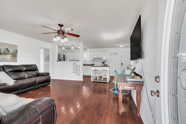 living room featuring ceiling fan, sink, and dark hardwood / wood-style floors