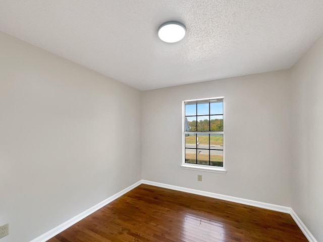 spare room featuring a textured ceiling and dark wood-type flooring