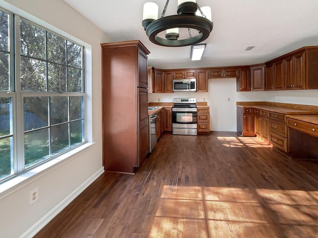 kitchen featuring appliances with stainless steel finishes, dark hardwood / wood-style floors, and hanging light fixtures