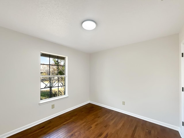 empty room with a textured ceiling and dark hardwood / wood-style floors