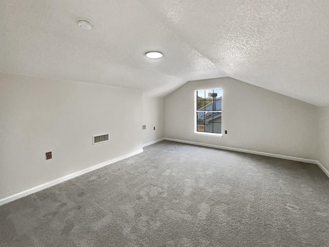 bonus room featuring dark carpet, a textured ceiling, and vaulted ceiling