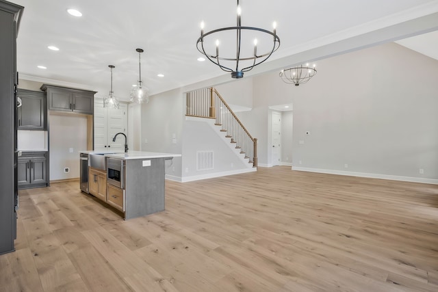 kitchen with a kitchen island with sink, sink, light hardwood / wood-style flooring, gray cabinets, and hanging light fixtures