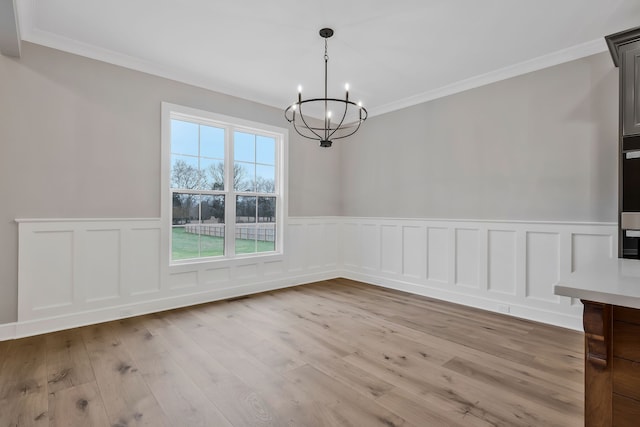 unfurnished dining area with ornamental molding, light hardwood / wood-style flooring, and a notable chandelier