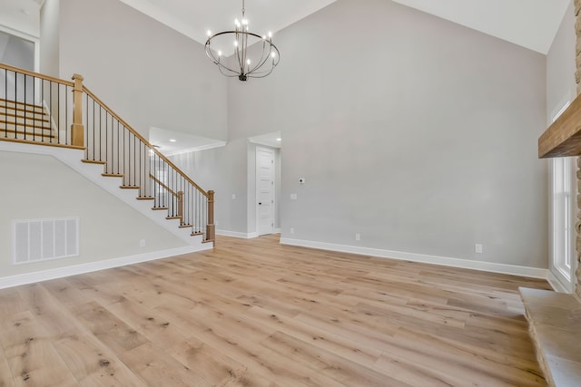 foyer entrance with light hardwood / wood-style flooring, high vaulted ceiling, and an inviting chandelier