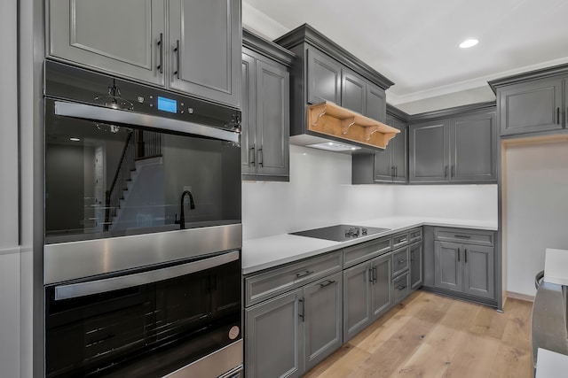 kitchen with light wood-type flooring, black electric cooktop, gray cabinets, and double oven