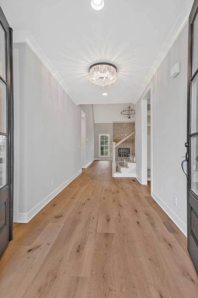 interior space with light wood-type flooring, crown molding, and a chandelier