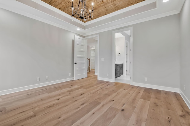 empty room featuring a notable chandelier, light hardwood / wood-style floors, a raised ceiling, and wooden ceiling