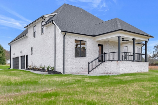 rear view of property with a porch, a yard, a garage, and ceiling fan