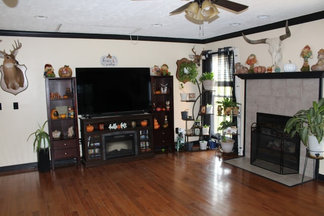 living room featuring dark wood-type flooring, crown molding, and a tile fireplace