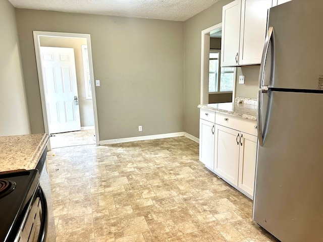 kitchen featuring white cabinetry, light stone countertops, stainless steel fridge, stove, and a textured ceiling