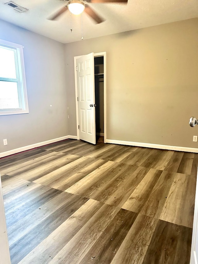 unfurnished bedroom featuring hardwood / wood-style floors, a closet, and ceiling fan