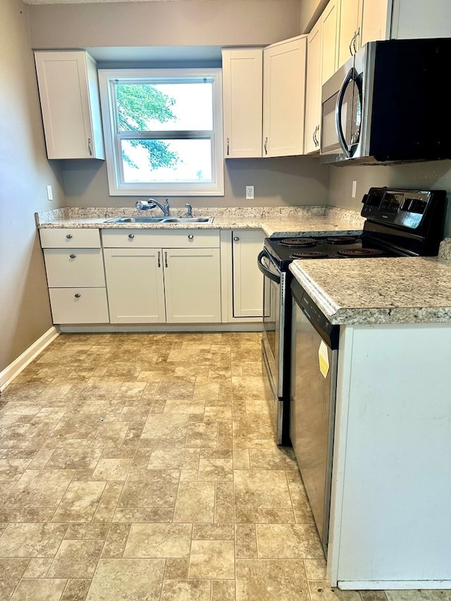 kitchen featuring electric range, sink, white cabinets, and light stone countertops