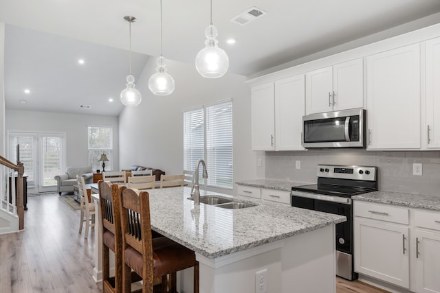 kitchen with hanging light fixtures, an island with sink, appliances with stainless steel finishes, white cabinetry, and sink