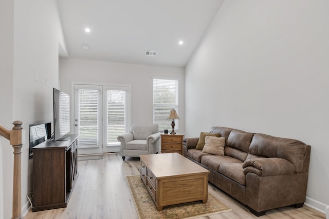 living room with high vaulted ceiling and light wood-type flooring