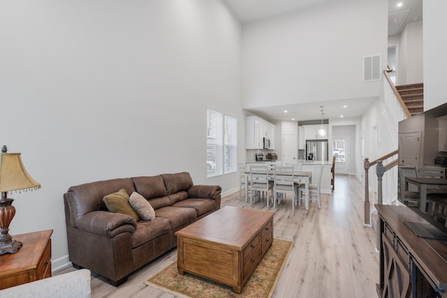 living room with a high ceiling and light wood-type flooring