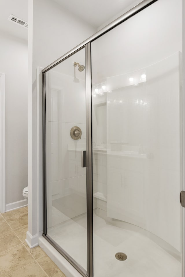 bathroom featuring tile patterned floors, toilet, and walk in shower