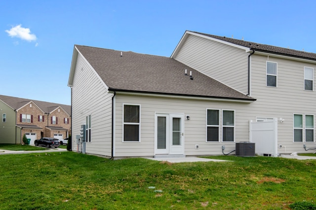 rear view of house with central AC unit, a garage, and a lawn