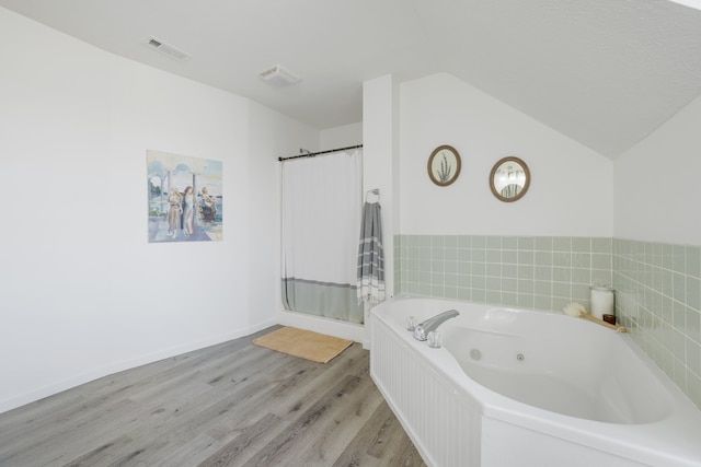 bathroom with vaulted ceiling, independent shower and bath, and wood-type flooring