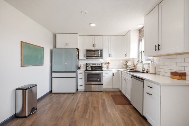 kitchen featuring wood-type flooring, sink, white cabinetry, appliances with stainless steel finishes, and tasteful backsplash