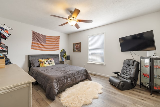 bedroom featuring ceiling fan, a textured ceiling, and light hardwood / wood-style flooring