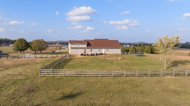 rear view of house with a rural view and a lawn