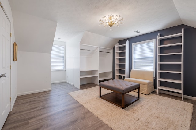 walk in closet featuring vaulted ceiling, a chandelier, and hardwood / wood-style floors