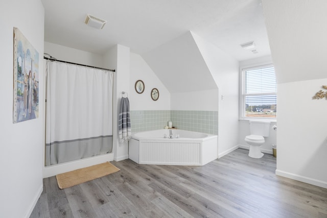 bathroom featuring toilet, shower with separate bathtub, hardwood / wood-style flooring, and vaulted ceiling