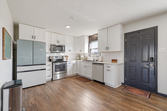 kitchen with sink, appliances with stainless steel finishes, wood-type flooring, and white cabinets