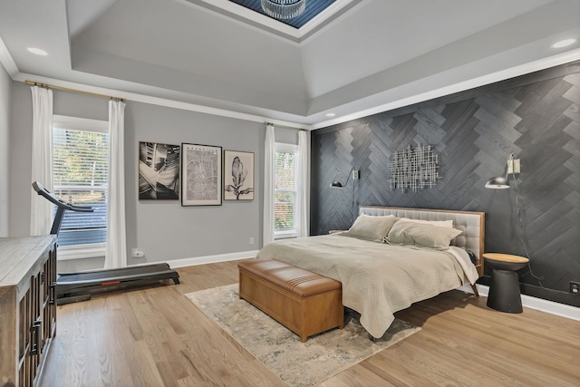 bedroom with light hardwood / wood-style floors and a tray ceiling