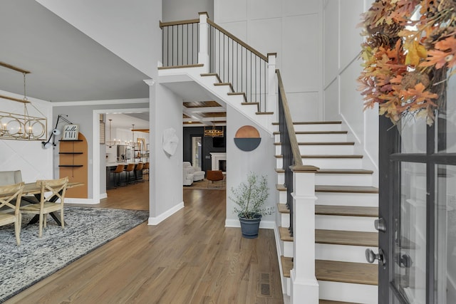 foyer entrance with crown molding, a notable chandelier, and hardwood / wood-style floors