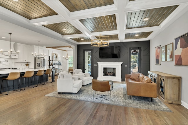 living room featuring light hardwood / wood-style floors, ornamental molding, beam ceiling, and coffered ceiling