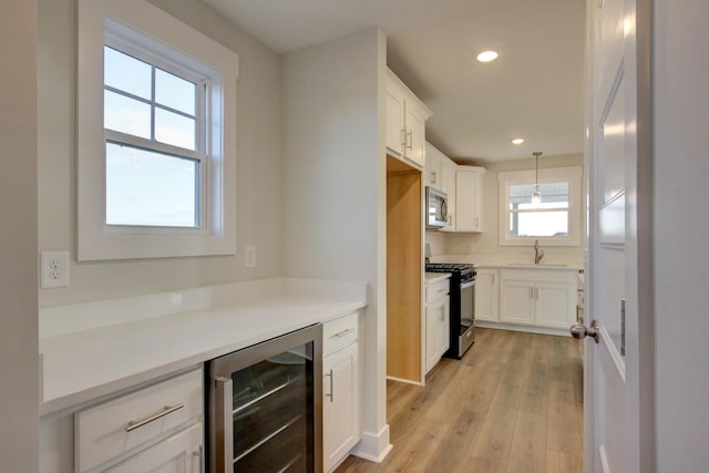 kitchen featuring sink, wine cooler, hanging light fixtures, appliances with stainless steel finishes, and white cabinetry