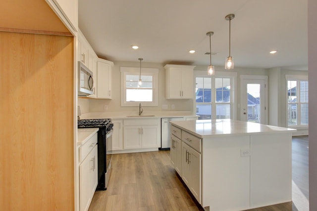 kitchen with sink, a kitchen island, pendant lighting, and appliances with stainless steel finishes